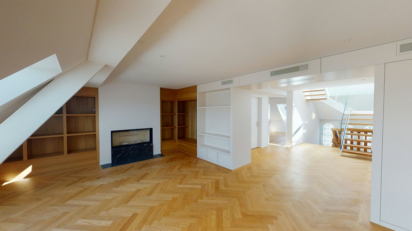 Moderno appartamento mansardato con pavimenti in legno e camino.