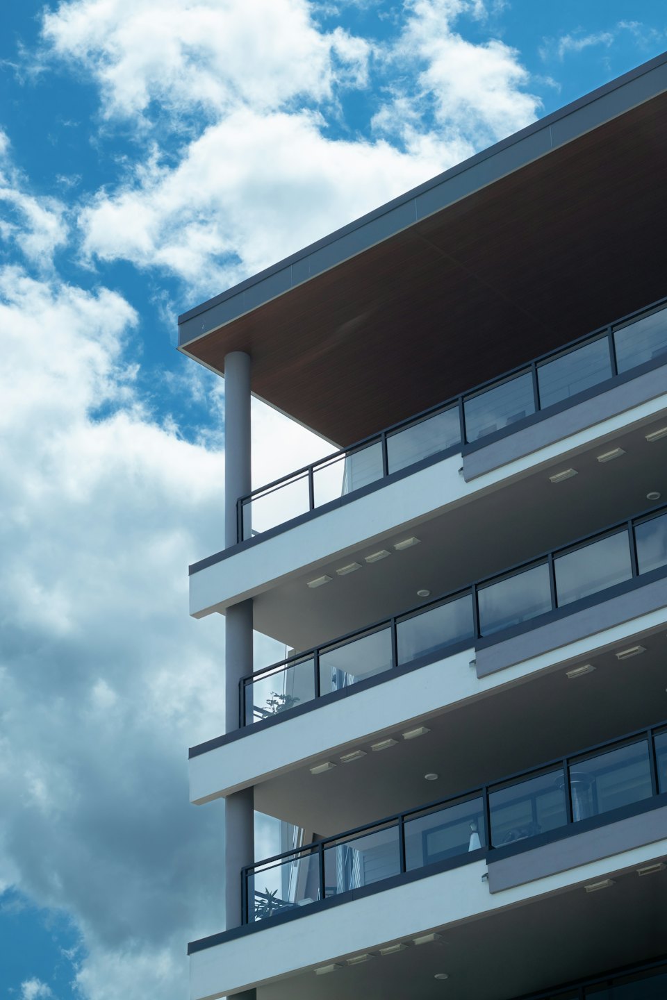 Moderno palazzo residenziale con balconi in vetro sotto un cielo azzurro.
